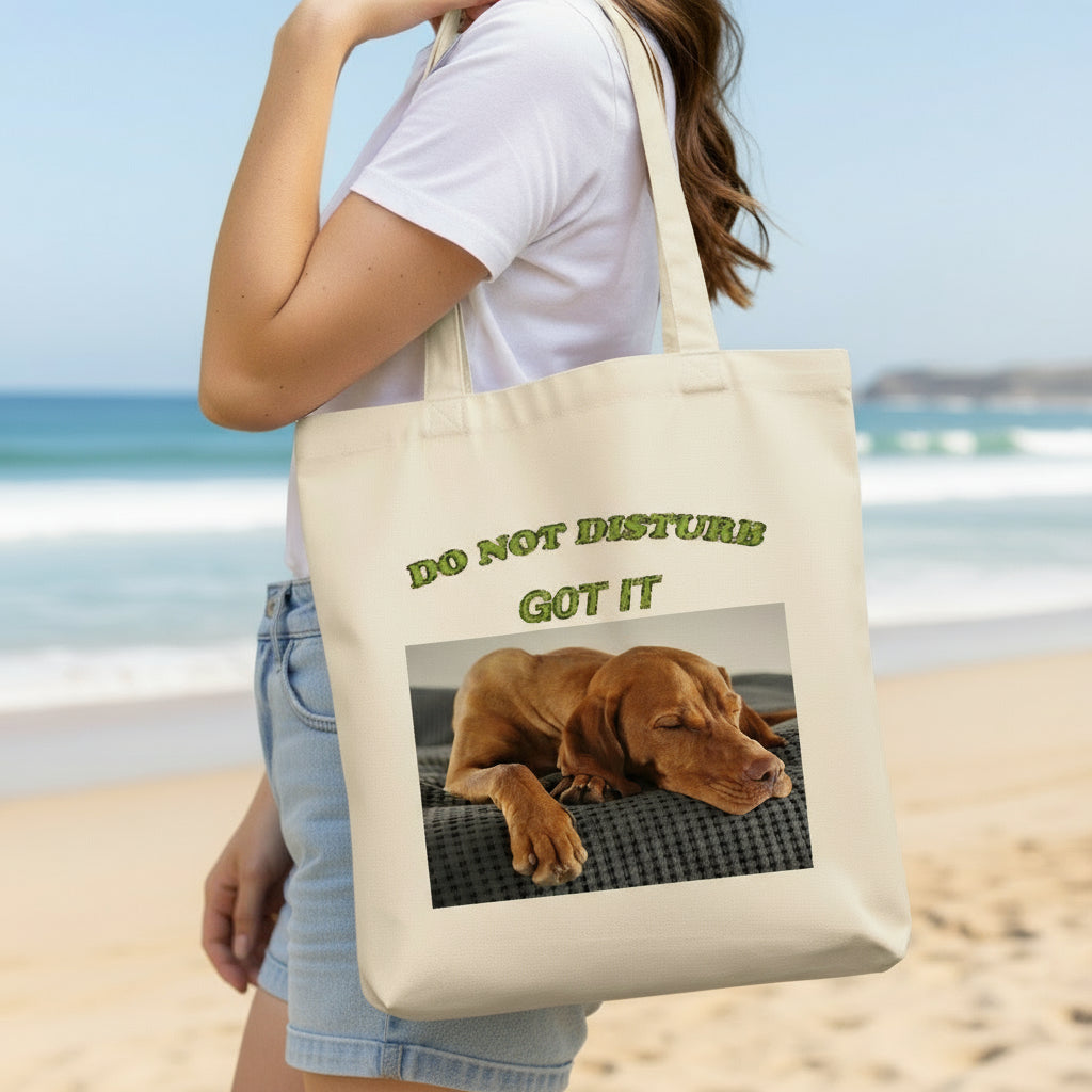 Person holding a tote bag with a dog graphic and text 'DO NOT DISTURB GOT IT'.