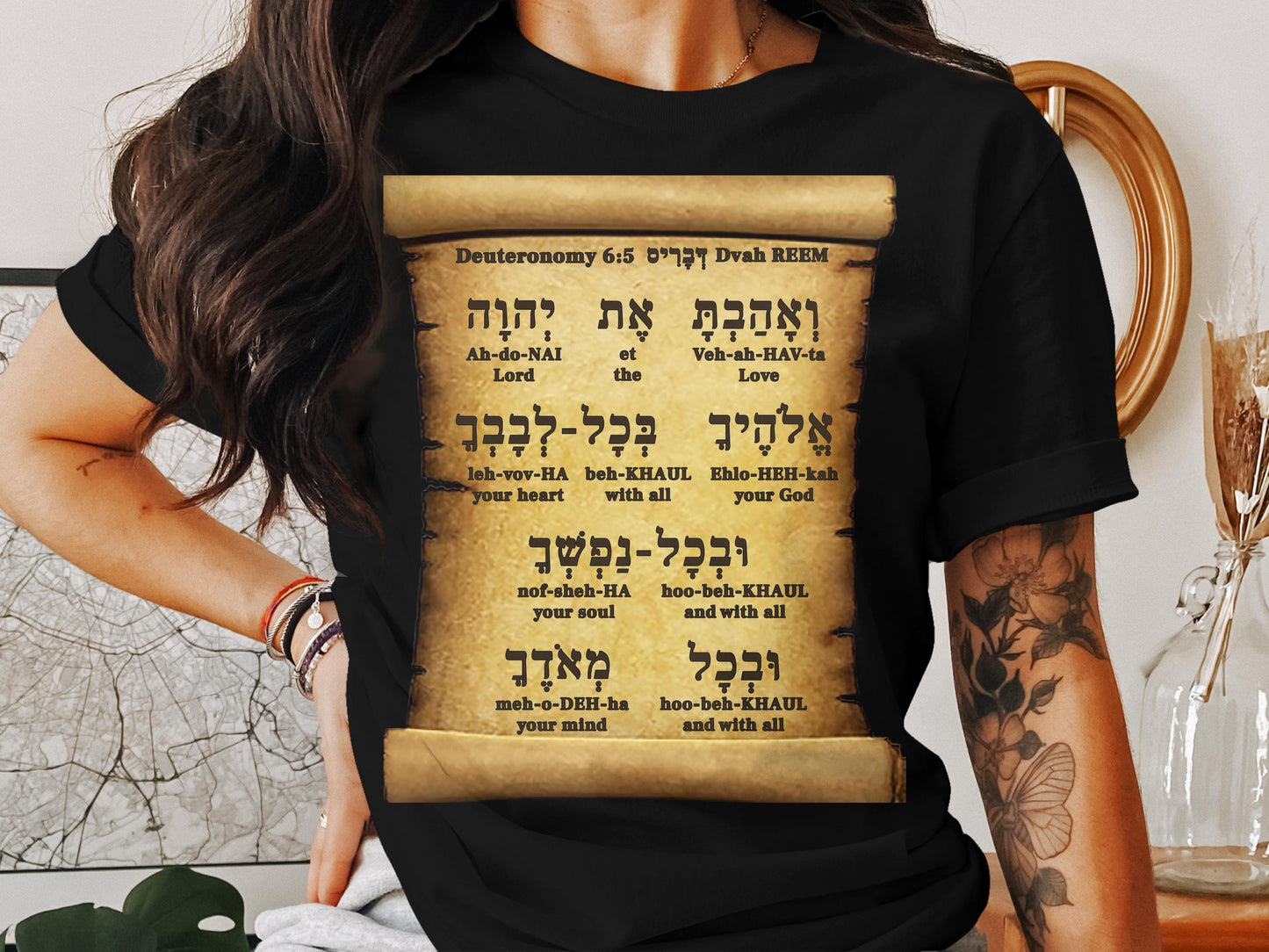 Person wearing a black t-shirt with a printed design of a Torah scroll.
