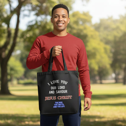 Man holding a black tote bag with religious text in a park