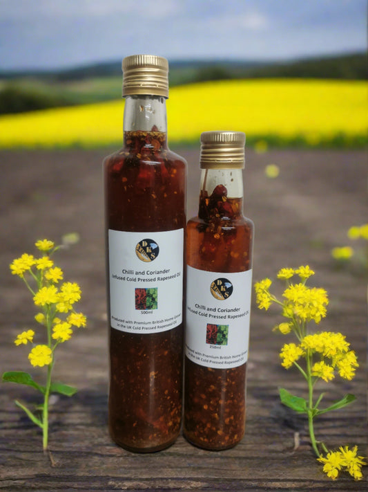 Chilli and Coriander infused rapeseed oil is in a glass bottle with some bits of crushed chilies, whole chillies and coriander in the bottle as well as the rapeseed oil.